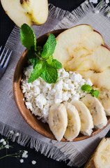 healthy food concept, top view, cottage cheese with banana, apple and a sprig of mint on a black table
