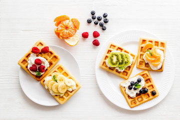 Belgian waffles with creamy cheese and berries on white background top-down