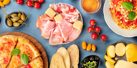 Italian food panorama. Pizza, pasta, cheese, ham, capers, wine, tomatoes, olives, a flat lay © laplateresca
