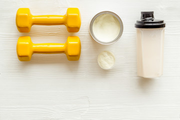 Sport diet. Protein shake near dumbbells on white background top-down flat lay copy space