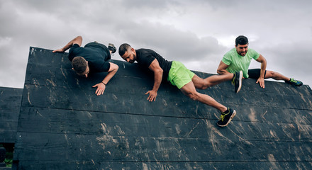 Group of participants in an obstacle course climbing an inverted wall