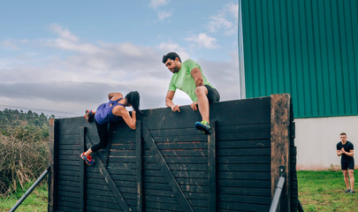 Group of participants in an obstacle course climbing a wall