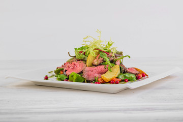 salad with potatoes and roast beef with green salad on a white wooden background