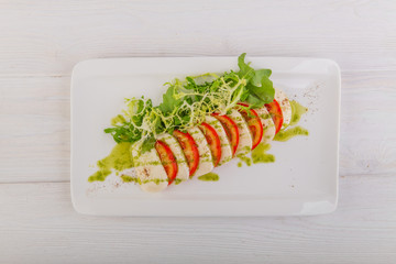 caprese with pesto on a white wooden background
