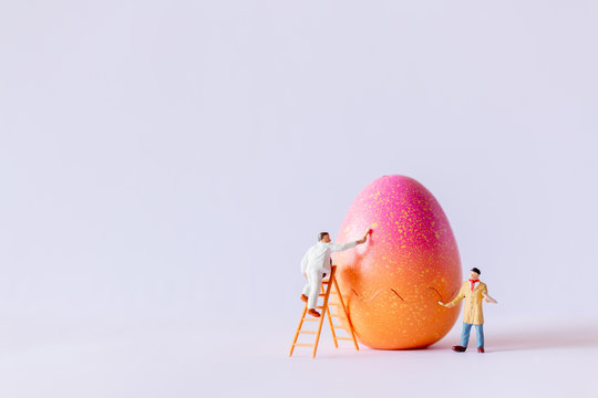 Miniature people painting Easter-eggs for Easter day