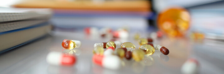 Focus on medications on workplace. Golden round sedative pills and capsules. Tired businesswoman...