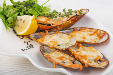 baked mussels with cheese on a white wooden background