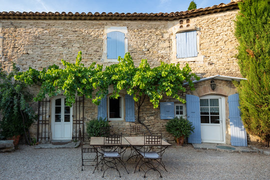 A typical French house in Provence, with blue shuttered windows and an al fresco dining area