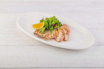 chicken breast with green salad on a white wooden background