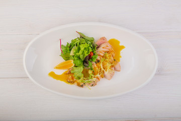chicken breast with green salad on a white wooden background
