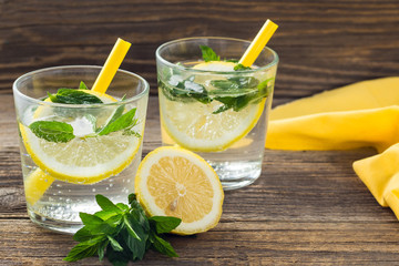 Lemonade or mojito cocktail with lemon and mint with ice. Cold summer refreshing drink decorated with yellow napkin