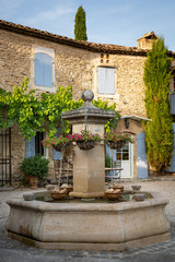 Hanging baskets on a fountain in the courtyard of a typical house in Provence, France