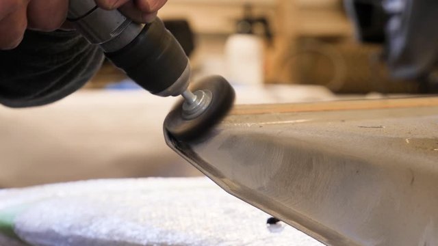 Using a wire brush on a rotary tool to clean the joint of an automobile door or some body part after a collision repair and before painting