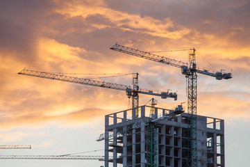 construction site with cranes against the background of bright evening clouds