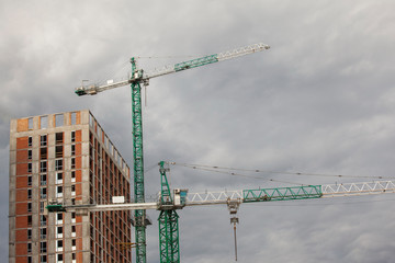 construction site with cranes against the cloudy sky
