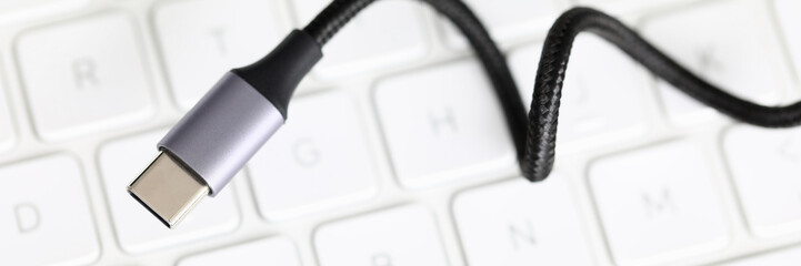 Usb type c cable against laptop keyboard background. Fast charge concept. Smartphone accessories closeup