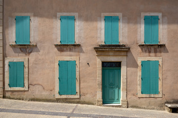Fototapeta na wymiar A beautiful house facade with matching blue coloured door and window shutters in a village in Provence, France