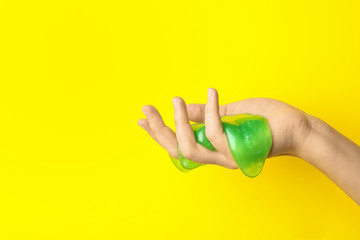 Fototapeta na wymiar Woman playing with green slime on yellow background, closeup. Antistress toy