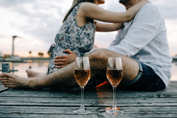 Romantic Couple sitting on the pier with red wine.