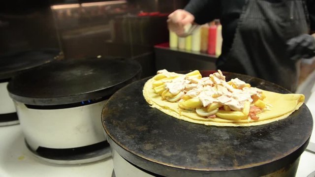 Cooking delicious pancakes. Female making pancakes on an hot electric stove. Preparing delicious and sweet food on the street. Stuffed pancakes. The process of cooking crepes. Girl preparing tasty mea