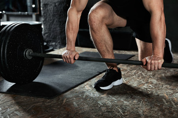 Fototapeta na wymiar Man lifting barbell in modern gym, closeup