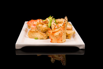 crab legs in a batter with green onions on a black background