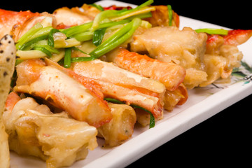 crab legs in a batter with green onions on a black background