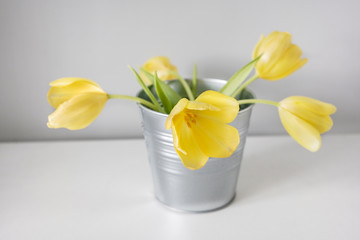 Beautiful spring yellow tulips in an abstract vase on the shelf, interior, sunny room