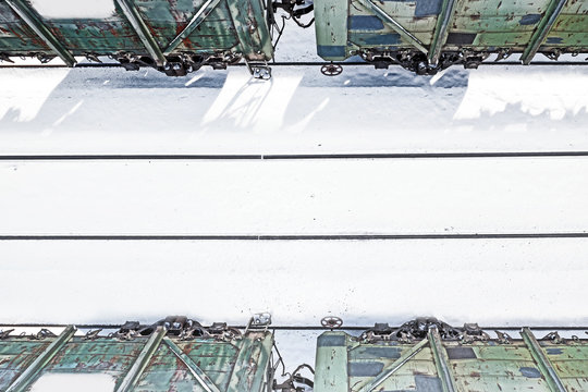 empty railway track of railroad station with weathered cargo train cars parked on parallel tracks abstract transportation landscape against white snow winter background. Aerial top down closeup view