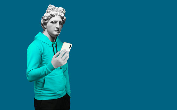 Naklejka Modern art collage. Concept portrait of a man  holding mobile smartphone using app texting sms message. Gypsum head of of Apollo. Man in suit. On a blue background.