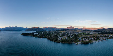 XXL panoramic evening sunset high angle aerial drone view of the town of Wanaka, a popular ski and summer resort town located at Lake Wanaka in the Otago region of the South Island of New Zealand.