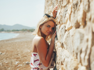 Young woman leaning to the stone wall