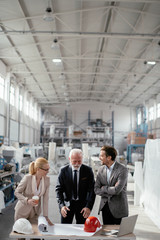 Colleagues working on project. Team of architects discussing business in factory. 