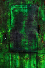 Green dark grunge wall. Hangar door with bright green paint and rust.