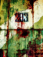 Grunge metal door of an abandoned military hangar from Russia with camouflage green and white paint and number 203. The rusty metal door is covered with blood spatter and cracks.