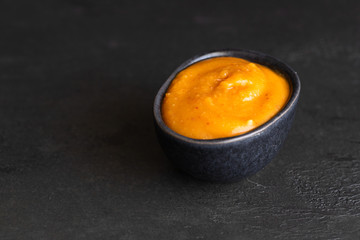 Almogrote, famous La Gomera cheese  paste, in black ceramic bowl on background. Its appetizer in many restaurants in Canary Islands made from hard cheese, peppers, olive oil and garlic