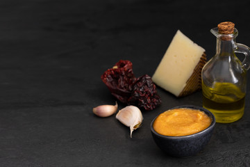 Fototapeta na wymiar Almogrote, La Gomera cheese paste, with their ingredients hard cheese, peppers, olive oil and garlic on black background. It is popular appetizer in many restaurants in Canary Islands