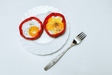 Aesthetic and beautiful scrambled eggs with peppers and seasonings on a light white plate on a neutral white background. Next to the food plate there is 1 fork. A delicious breakfast picture