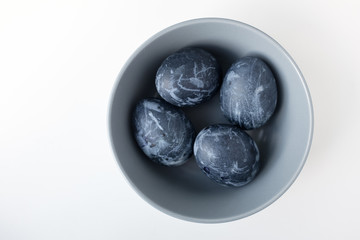 Naturally dyed blue eggs prepared for Easter on white background. Happy Easter card. Easter background with Easter eggs in a ceramic gray bowl. Background with easter eggs. Top view 