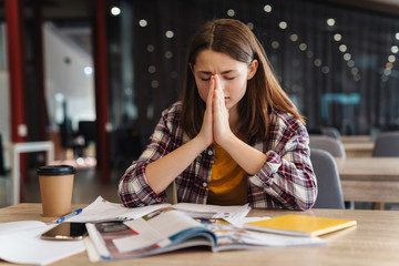 Image of focused girl sitting with palms together while doing homework
