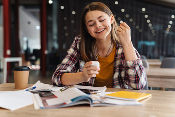 Image of happy nice girl using wireless earphone while doing homework