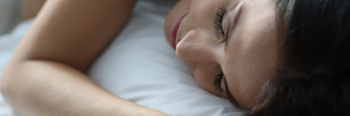 Portrait of attractive cute woman slumbering on white bed. Pretty brunette in sleepwear lying on...