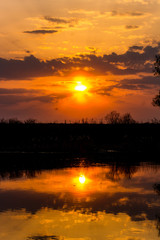 Colorful sunset behind the clouds above the water, vertical view