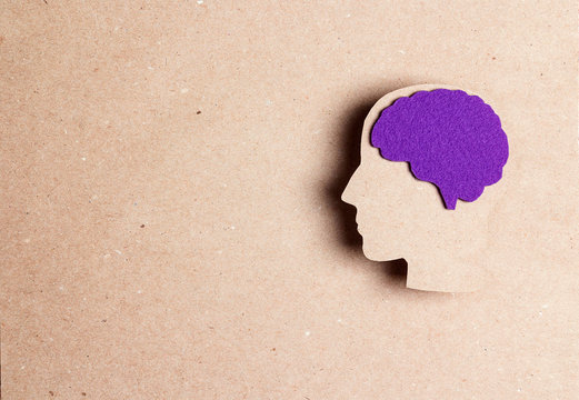 Head silhouette with a purple brain on a brown background with copy space.