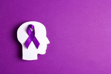 Purple awareness ribbon and head silhouette on a purple background.