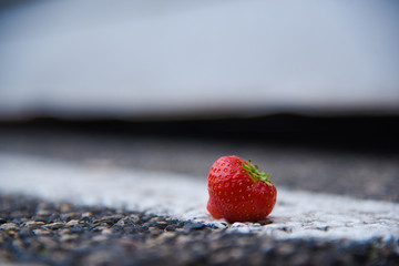 Ripe strawberries lie on the asphalt