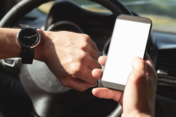 Driver is looking on a blank screen mobile phone with copy space and is checking a time on his wrist watch close up.