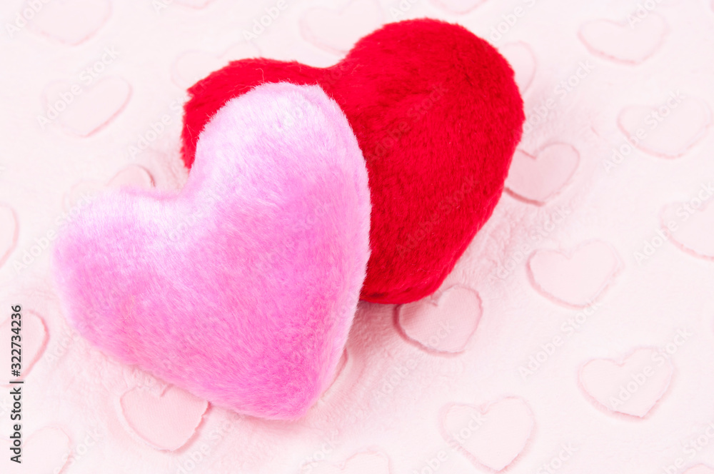 Wall mural pair of fluffy pink and red plush hearts sitting on a valentine's day background