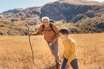 Senior man with grandson on country walk in autumn.