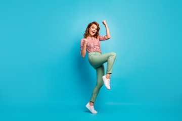 Fototapeta na wymiar Yeah. Full length profile photo of beautiful lady crazy emotions raise fists win money lottery wear casual red white shirt green pants footwear isolated blue color background